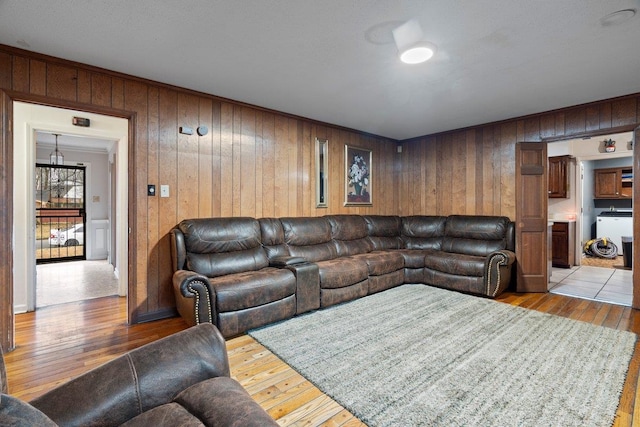 living room with crown molding, wooden walls, and light hardwood / wood-style floors