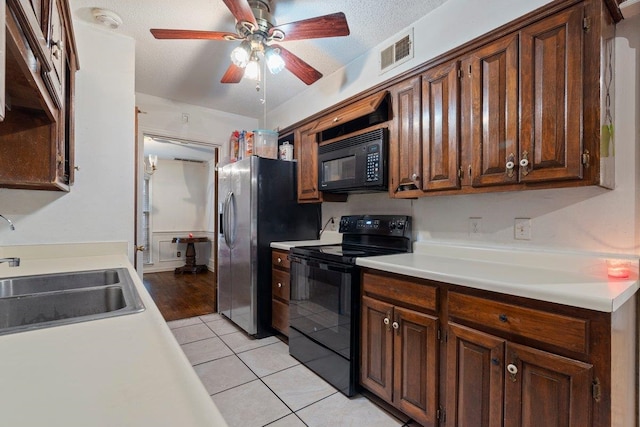 kitchen with light tile patterned flooring, sink, ceiling fan, black appliances, and a textured ceiling