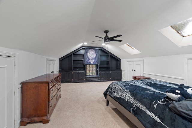 carpeted bedroom featuring lofted ceiling with skylight and ceiling fan