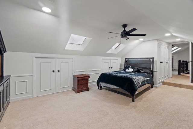 bedroom with light carpet, ceiling fan, lofted ceiling, and multiple closets