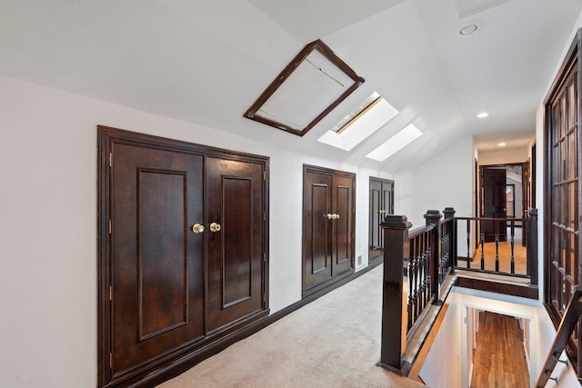 hall with carpet flooring and vaulted ceiling with skylight