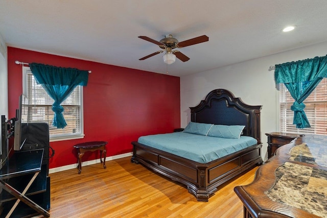 bedroom featuring multiple windows, wood-type flooring, and ceiling fan