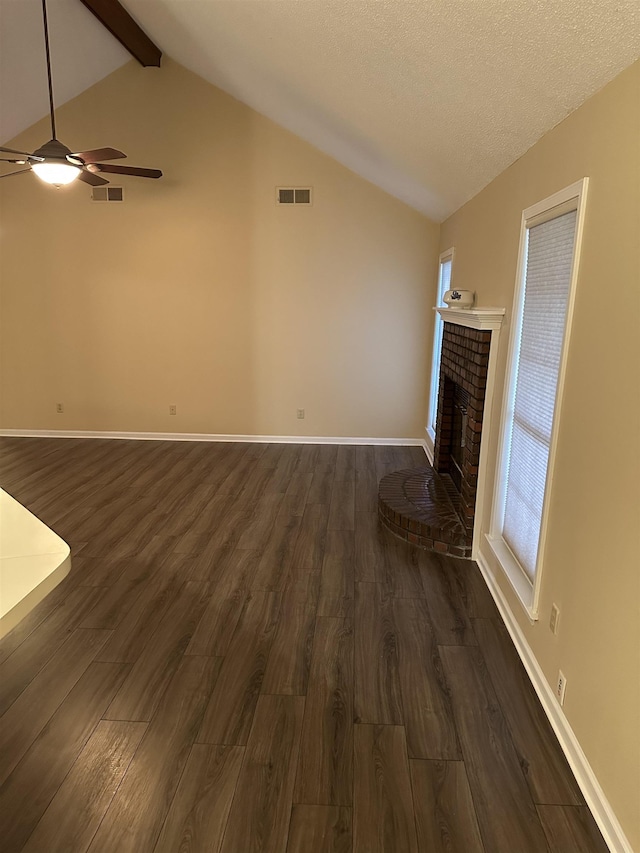 unfurnished living room with lofted ceiling with beams, a brick fireplace, dark wood-type flooring, and a textured ceiling