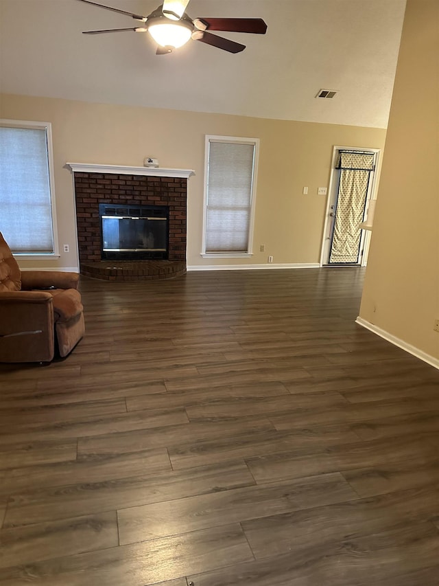 unfurnished living room with vaulted ceiling, a brick fireplace, dark hardwood / wood-style floors, and ceiling fan