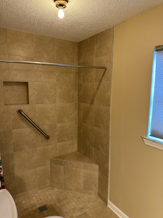 bathroom featuring toilet, a textured ceiling, and a tile shower