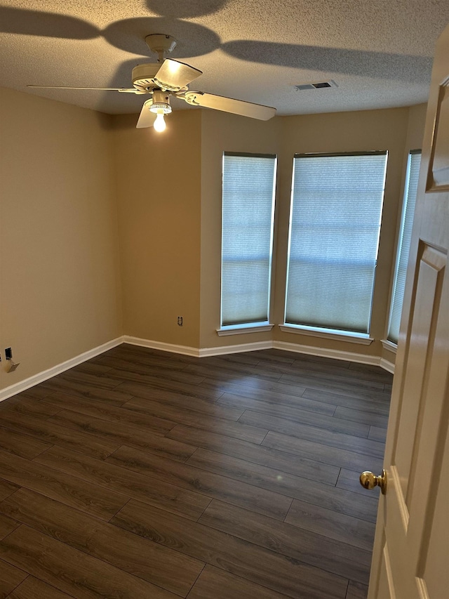 unfurnished room with dark hardwood / wood-style flooring, ceiling fan, and a textured ceiling