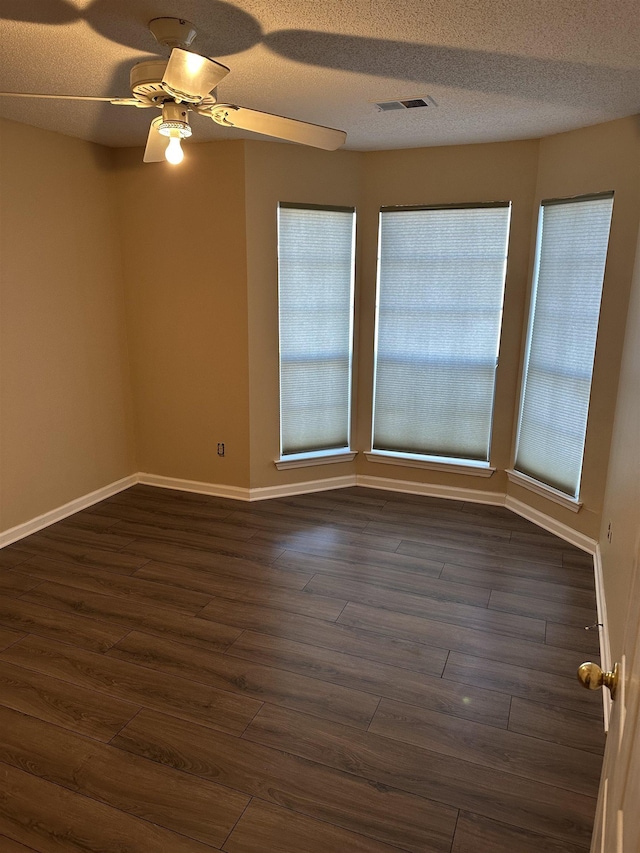 spare room with dark wood-type flooring, a textured ceiling, and plenty of natural light