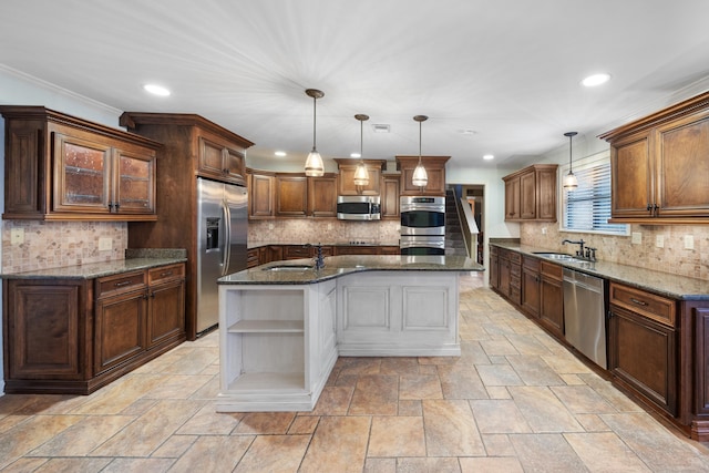 kitchen featuring sink, decorative light fixtures, dark stone counters, stainless steel appliances, and a kitchen island with sink