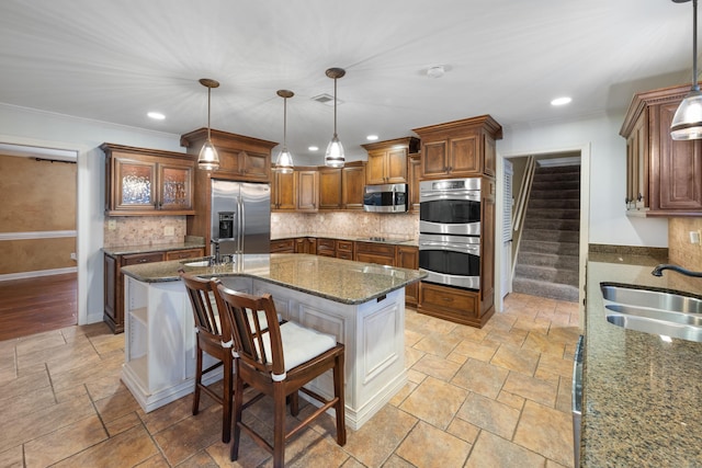 kitchen featuring stainless steel appliances, decorative light fixtures, sink, and dark stone countertops