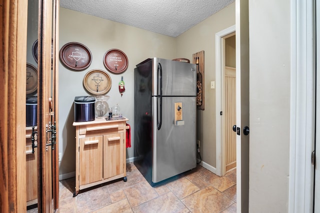 kitchen featuring a textured ceiling and stainless steel refrigerator