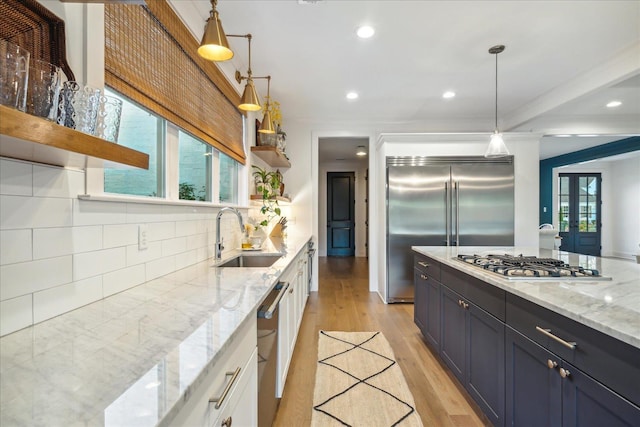 kitchen featuring stainless steel appliances, sink, pendant lighting, and white cabinets