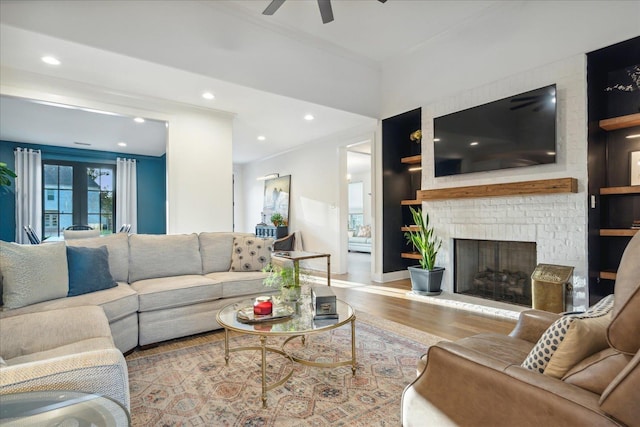 living room with ceiling fan, light hardwood / wood-style floors, and a brick fireplace