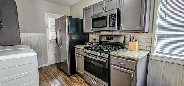 kitchen featuring gray cabinets, dark hardwood / wood-style floors, washer / clothes dryer, backsplash, and stainless steel appliances