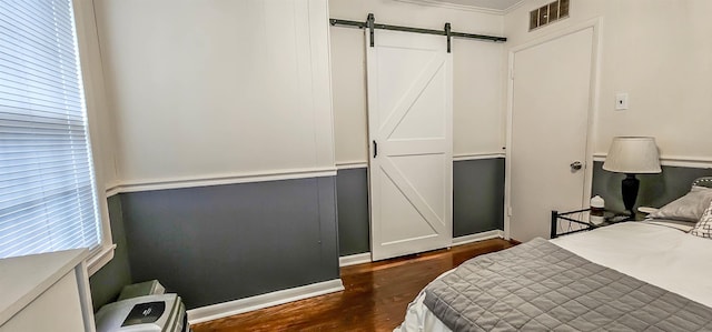 bedroom featuring dark wood-type flooring and a barn door