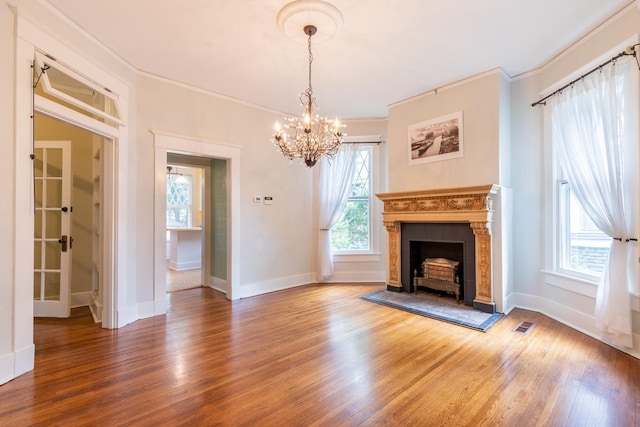 unfurnished living room with an inviting chandelier, crown molding, wood-type flooring, and a tile fireplace