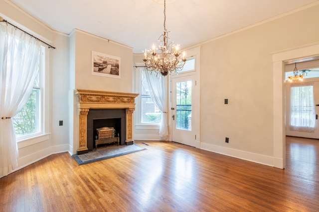 unfurnished living room with an inviting chandelier, crown molding, wood-type flooring, and a wealth of natural light