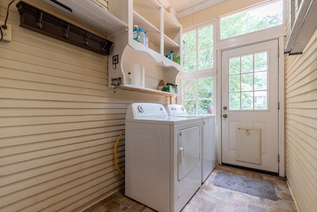 washroom with washing machine and clothes dryer and wood walls