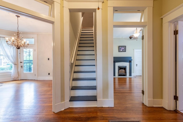 staircase with a notable chandelier, hardwood / wood-style flooring, and a fireplace