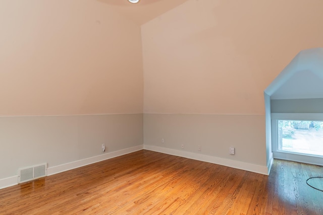 additional living space with hardwood / wood-style flooring and vaulted ceiling