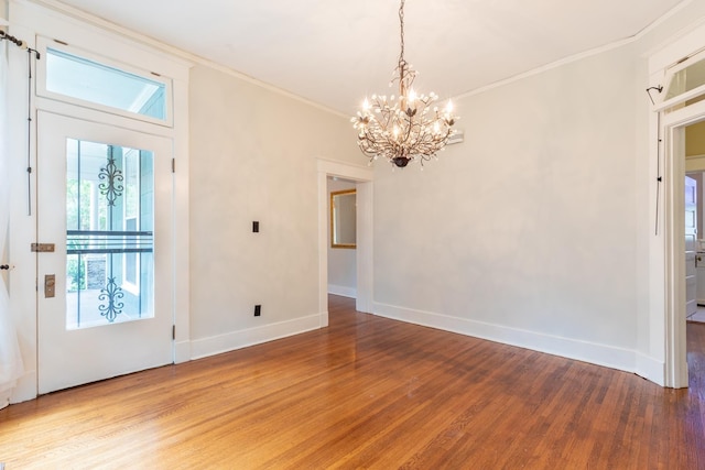 interior space featuring hardwood / wood-style flooring, ornamental molding, and an inviting chandelier