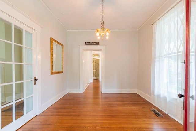 interior space featuring crown molding, hardwood / wood-style floors, an inviting chandelier, and french doors