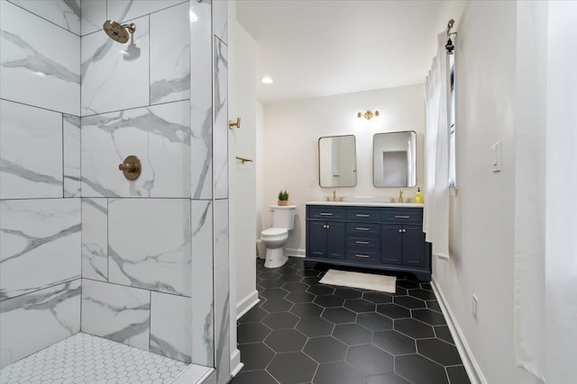 bathroom with vanity, tile patterned flooring, toilet, and tiled shower