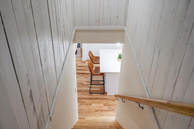 stairway with hardwood / wood-style flooring and wood walls