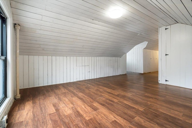 bonus room featuring vaulted ceiling, dark wood-type flooring, and wood walls