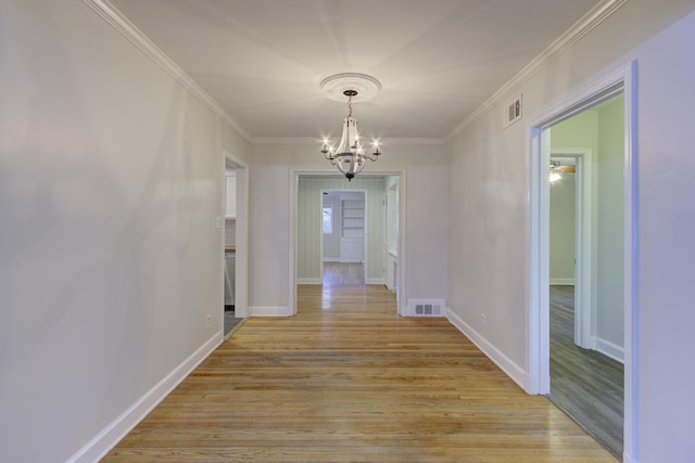 hall with an inviting chandelier, crown molding, and light hardwood / wood-style flooring