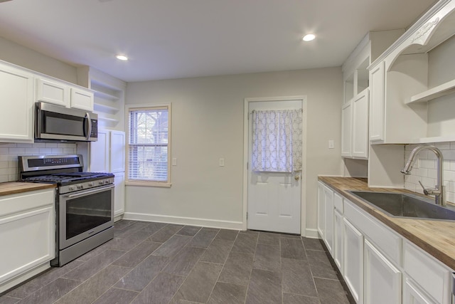 kitchen featuring butcher block counters, sink, white cabinets, stainless steel appliances, and backsplash