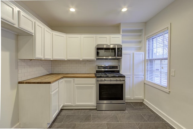 kitchen with tasteful backsplash, wood counters, appliances with stainless steel finishes, and white cabinets