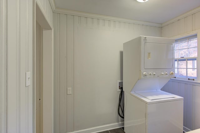 washroom with crown molding and stacked washer and dryer