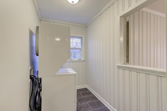 laundry area with crown molding, dark tile patterned floors, and stacked washing maching and dryer