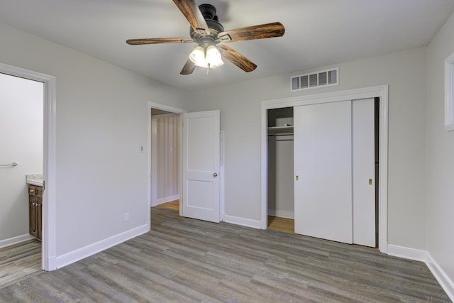 unfurnished bedroom with ceiling fan, a closet, connected bathroom, and light hardwood / wood-style flooring