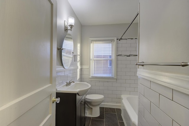 full bathroom with tile patterned floors, toilet, tiled shower / bath, tile walls, and vanity