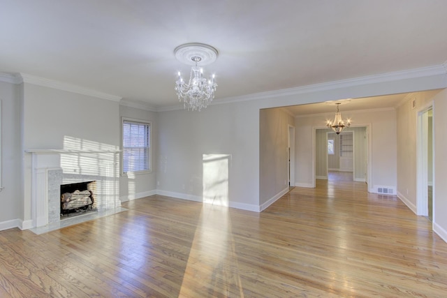 unfurnished living room with ornamental molding, a chandelier, and light hardwood / wood-style floors