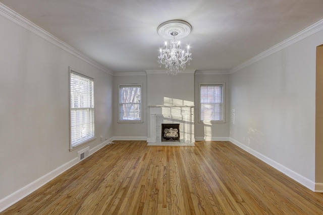 unfurnished living room with crown molding, an inviting chandelier, and light hardwood / wood-style flooring