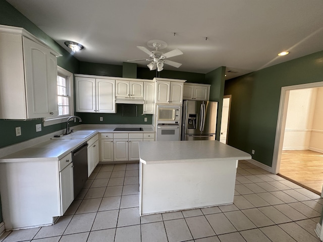 kitchen featuring light tile patterned flooring, sink, a center island, stainless steel appliances, and white cabinets