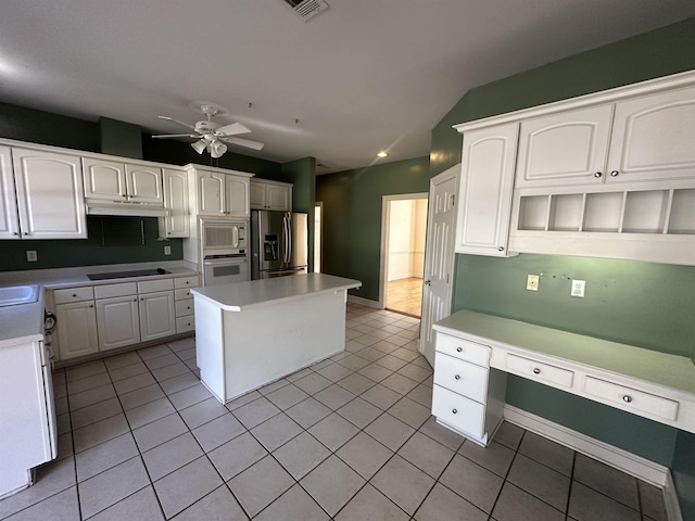 kitchen featuring white cabinetry, built in desk, light tile patterned floors, appliances with stainless steel finishes, and a kitchen island