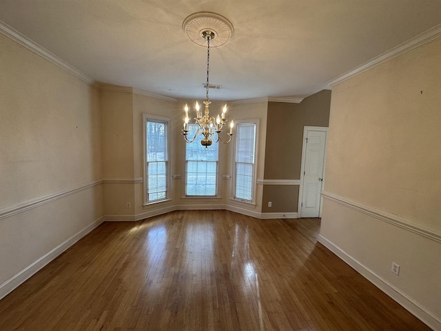 unfurnished dining area featuring wood-type flooring, ornamental molding, and a chandelier