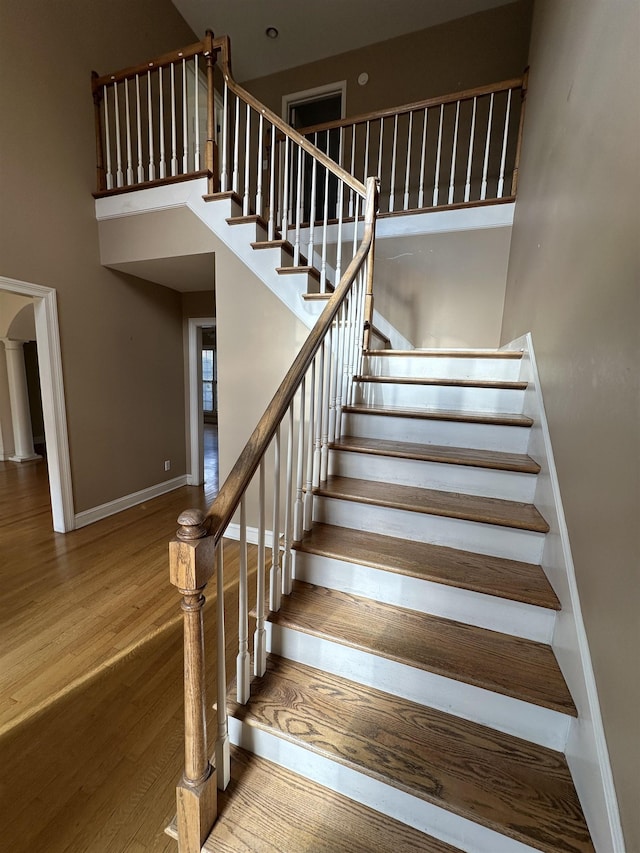 stairs featuring hardwood / wood-style floors and a towering ceiling