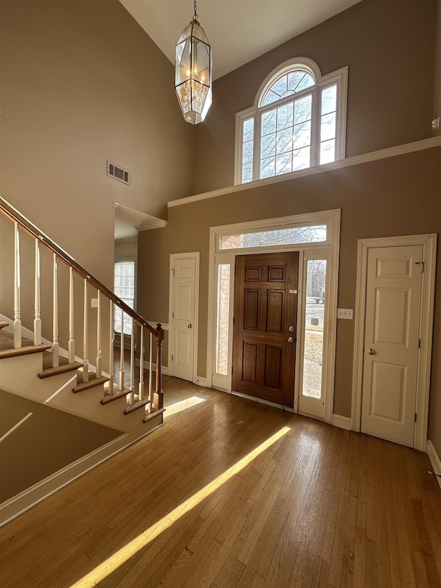 entrance foyer featuring hardwood / wood-style flooring, a wealth of natural light, a chandelier, and a towering ceiling