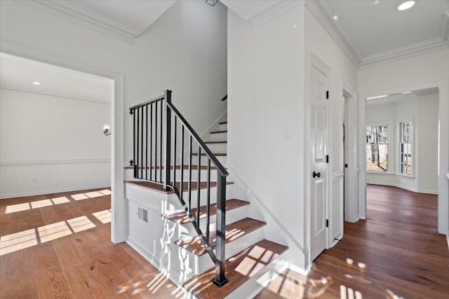 staircase with wood-type flooring and ornamental molding