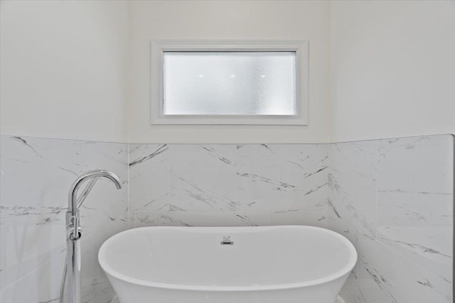 bathroom featuring a bath, tile walls, and a wealth of natural light