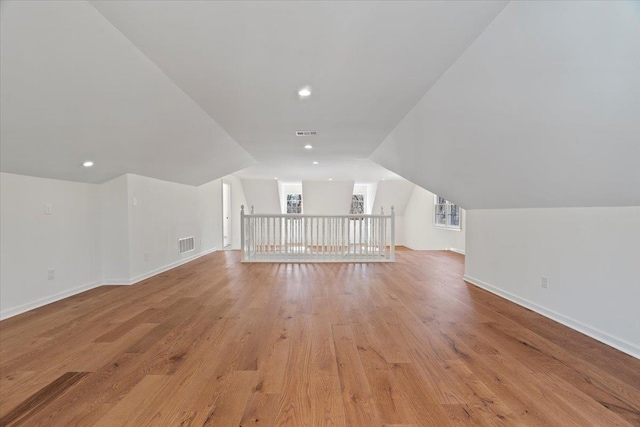 additional living space featuring vaulted ceiling and light hardwood / wood-style flooring