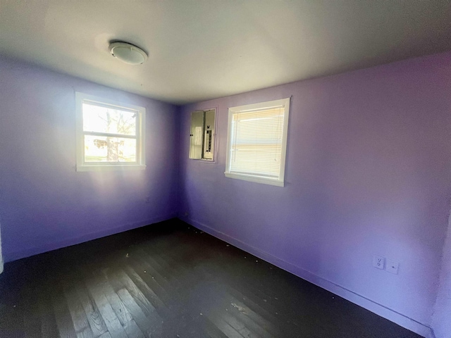 unfurnished room featuring electric panel and dark hardwood / wood-style flooring