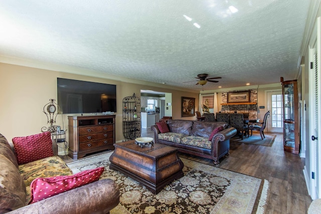 living room with hardwood / wood-style flooring, ceiling fan, ornamental molding, and a textured ceiling