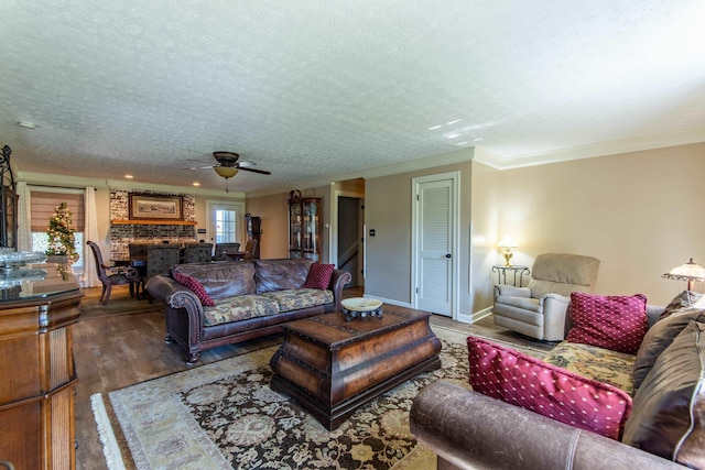 living room with wood-type flooring, ornamental molding, ceiling fan, and a textured ceiling