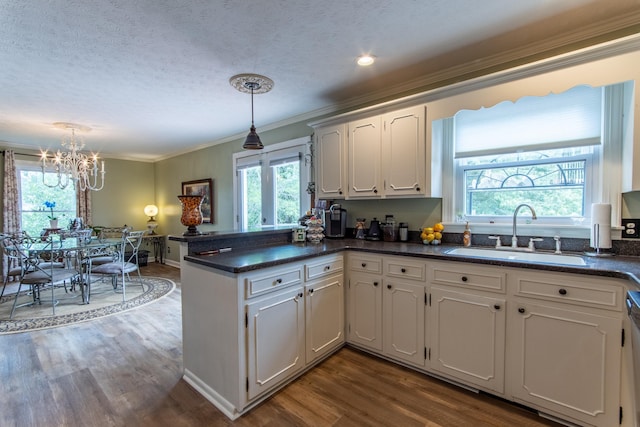 kitchen featuring sink, light hardwood / wood-style flooring, kitchen peninsula, pendant lighting, and white cabinets