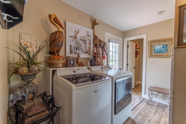 laundry area featuring washer and dryer, a textured ceiling, and light hardwood / wood-style flooring